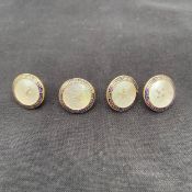A set of four early 20th century 18ct gold and mother-of-pearl buttons with enamelled greek key or