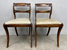 A pair of Regency faux rosewood dining chairs with acanthus carved back rails on sabre supports. H.