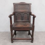 A 17th century Charles I oak armchair having a fluted and carved panel back with shaped arms over