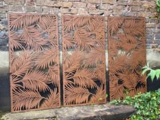 A set of three contemporary openwork metal foliate garden wall panels or screens with a rust