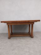 An early to mid 20th century Arts & Crafts style oak extending dining table with panel top raised on
