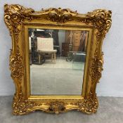 A vintage Rococo style wall mirror with rectangular bevelled plate in a gilt composite moulded