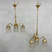 A pair of early 20th century brass chandeliers each with three scrolling branches terminating in