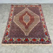 A Persian Bidjar rug with three central stepped diamond lozenges in a patterned field over a camel
