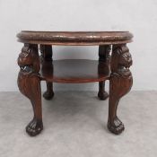 A mid century walnut coffee table with section veneered top on carved lion supports united by an