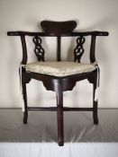 A Chinese hardwood corner chair fitted with squab cushion on stretchered supports. H.84cm.