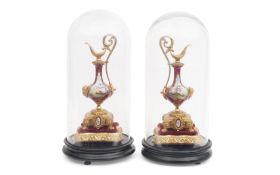 A PAIR OF LATE 19TH CENTURY GILT AND PORCELAIN EWERS UNDER GLASS DOMES