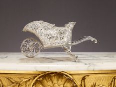 A GERMAN SILVER NOVELTY BOTTLE HOLDER IN THE FORM OF A WHEELBAROW C. 1890