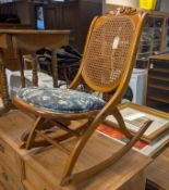 Cane Back Rocker With Blue And White Upholstered Seat.
