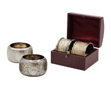 A cased pair of Victorian silver napkin rings, and one other pair of silver napkin rings.