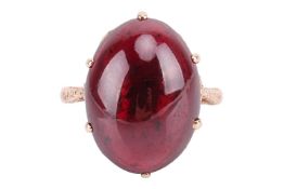 A garnet 'carbuncle' dress ring in 9ct gold, claw-set with an oval garnet cabochon of 20.0 x 15.2 x 