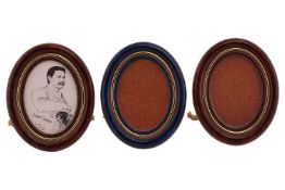 Three Must de Cartier gilt metal photo frames, of oval shape, a pair in brown and another in blue wi