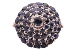A Thai princess ring set with sapphire; the domed and tiered ring head formed by a cluster of circul