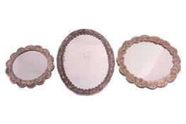 Three wedding mirrors with white metal frames; comprising an Egyptian oval mirror with floral decora