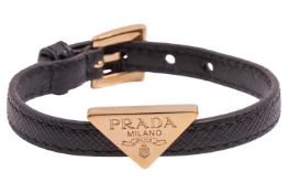 Prada - a triangle logo bracelet in black leather, gold-tone hardware, cased, in original box.some c