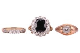 A group of three gem-set rings: The first a diamond three stone ring, comprising three claw-set roun