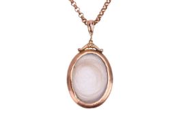 A locket pendant on a 9ct gold belcher chain, the oval locket glazed to both sides, encasing a lock 