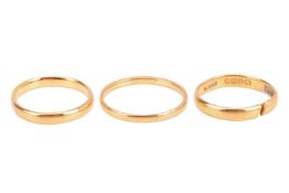 Three 22ct gold wedding bands; all comprising a court-shaped band, one of them pierced open, British
