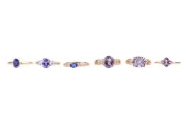 Six gold rings set with purple gemstones; to include a tanzanite and diamond cluster ring in size S,