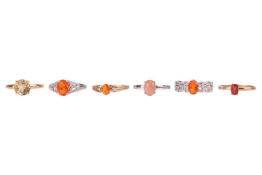 Six 9ct gold dress rings set with orange gemstones; to include an andesine solitaire in size S, an o