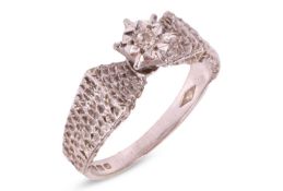 A single stone illusion-set diamond ring, set above textured, angled shoulders, in an 18 carat white