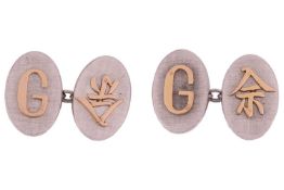 A pair of two-tone cufflinks with applied initials, the oval textured panels one set with the alphab