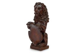 A CARVED OAK NEWEL POST FINIAL FORMED AS A SEATED LION HOLDING A SHIELD