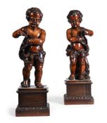 A PAIR OF CONTINENTAL CARVED WALNUT FIGURES OF PUTTI, PROBABLY EARLY 18TH CENTURY