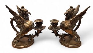 A pair of late 19th century dark brown patinated bronze griffin/wyvern candlesticks, on circular