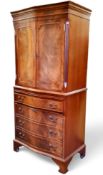 A reproduction mahogany serpentine cabinet on chest, with two panelled doors above brushing slide,