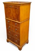 A reproduction yew cocktail cabinet, fall front with mirrored interior, above four blind drawers,