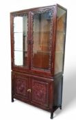 Oriental Furniture - a Chinese hardwood cabinet, pierced and carved fretwork glazed doors, with