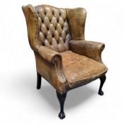 A George III Revival wingback armchair, in olive green leather, cabriole forelegs terminating with
