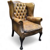 A George III Revival wingback armchair,  in olive green leather, cabriole forelegs terminating