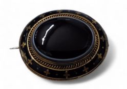 A Victorian gilt metal mourning brooch, oval banded onyx cabochon, banded black enamel border,