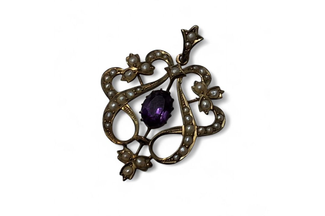 An Edwardian 9ct gold, amethyst and seed pearl drop pendant, the openwork mount set with seed pearls