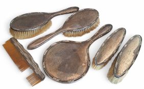 A silver dressing table set comprising hand mirror, a pair of hair brushes, a pair of clothes