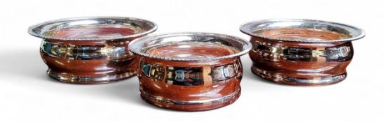 A pair of E.P.N.S. bottle coasters, draught turned bases, gadrooned rims, 15.5cm diam; another,