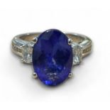 An 18ct white gold tanzanite and diamond ring, the central oval 4.52ct Tanzanite flanked by two oval