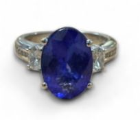 An 18ct white gold tanzanite and diamond ring, the central oval 4.52ct Tanzanite flanked by two oval