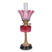 A LATE VICTORIAN BRASS AND CRANBERRY GLASS OIL LAMP