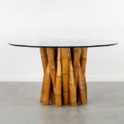 A Large Round Dining Table with a Bamboo Base and a Glass Top.