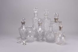 Eight cut and plain glass decanters, including four with silver collars