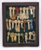 A collection of gilt metal and silk equestrian rosettes, 1923-1929, to a display case