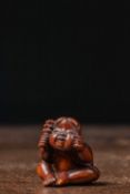 (R) NETSUKE OF A SEATED CHILD WITH RATTLE