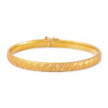 A TEXTURED HIGH KARAT GOLD BANGLE