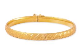 A TEXTURED HIGH KARAT GOLD BANGLE