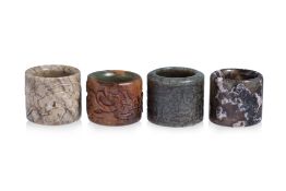 A GROUP OF FOUR JADE AND HARDSTONE THUMB RINGS