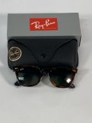 A pair of Ray-Bans Wayfarer Fleck sunglasses in black and tortoise with green classic lenses (RB2140