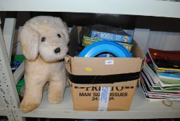 A box containing various jigsaws, 2 stuffed toys e